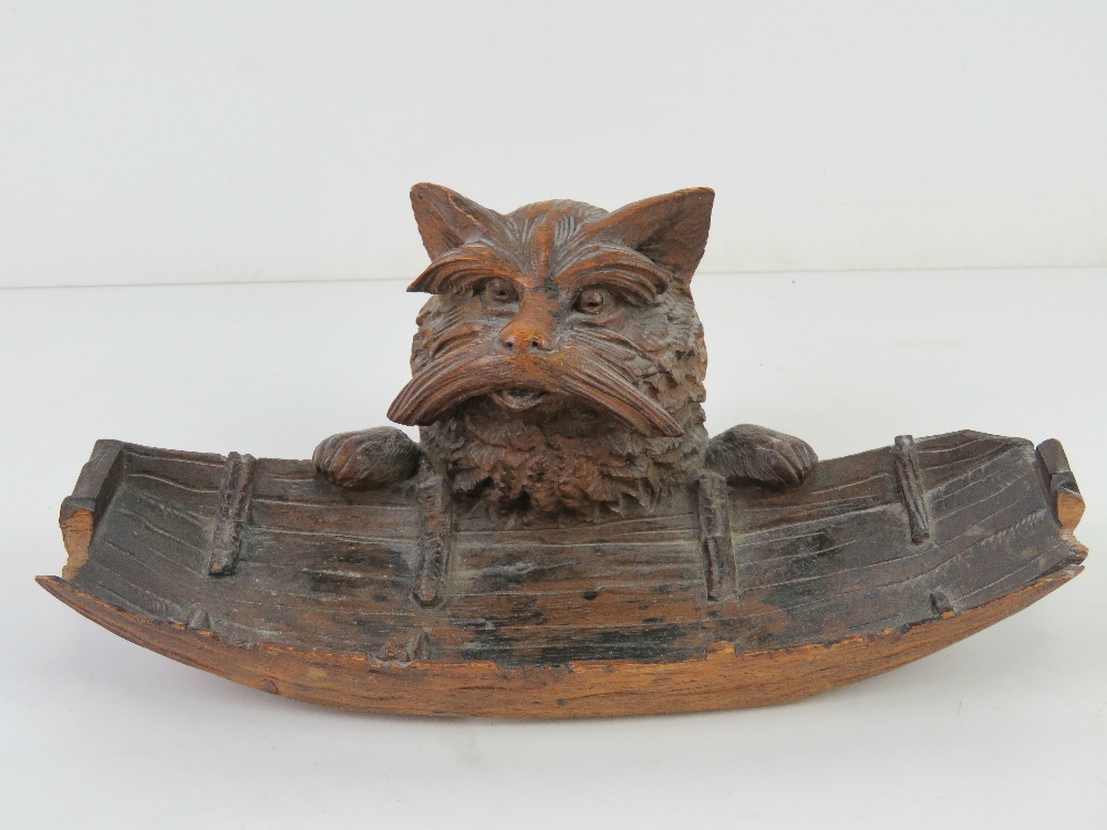 A black forest type carved wooden pen tray having beast peering over side of boat,
