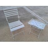 A single white bistro chair with white metal table having bee pattern.