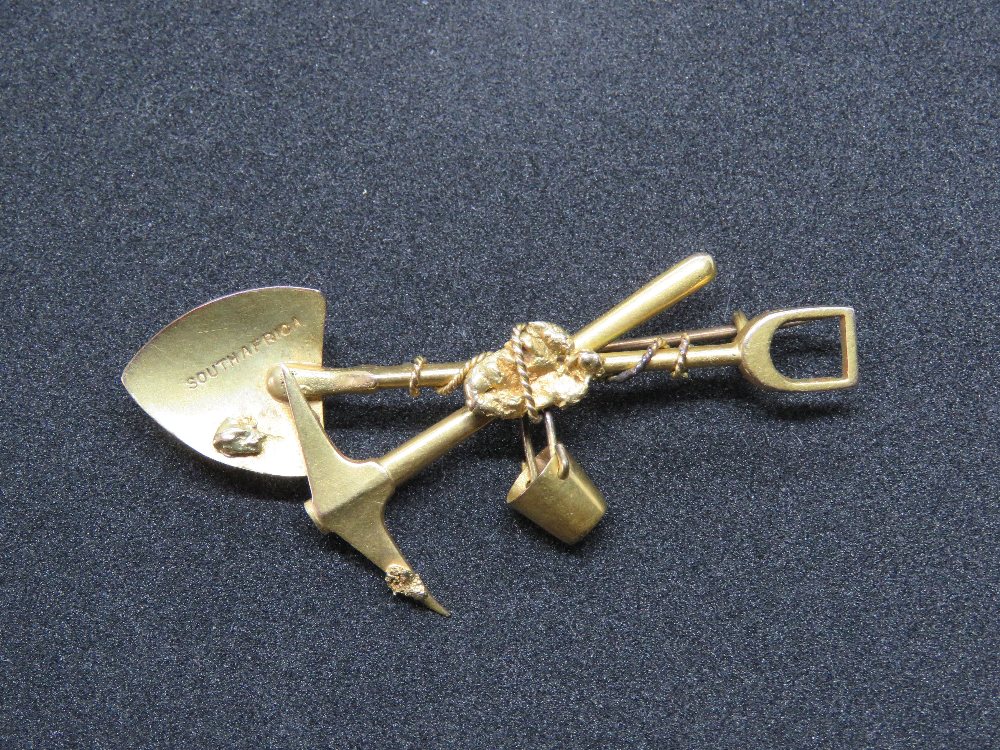 A 15ct gold South Africa mining themed brooch comprising pick, spade and bucket, stamped 15, 7.6g.