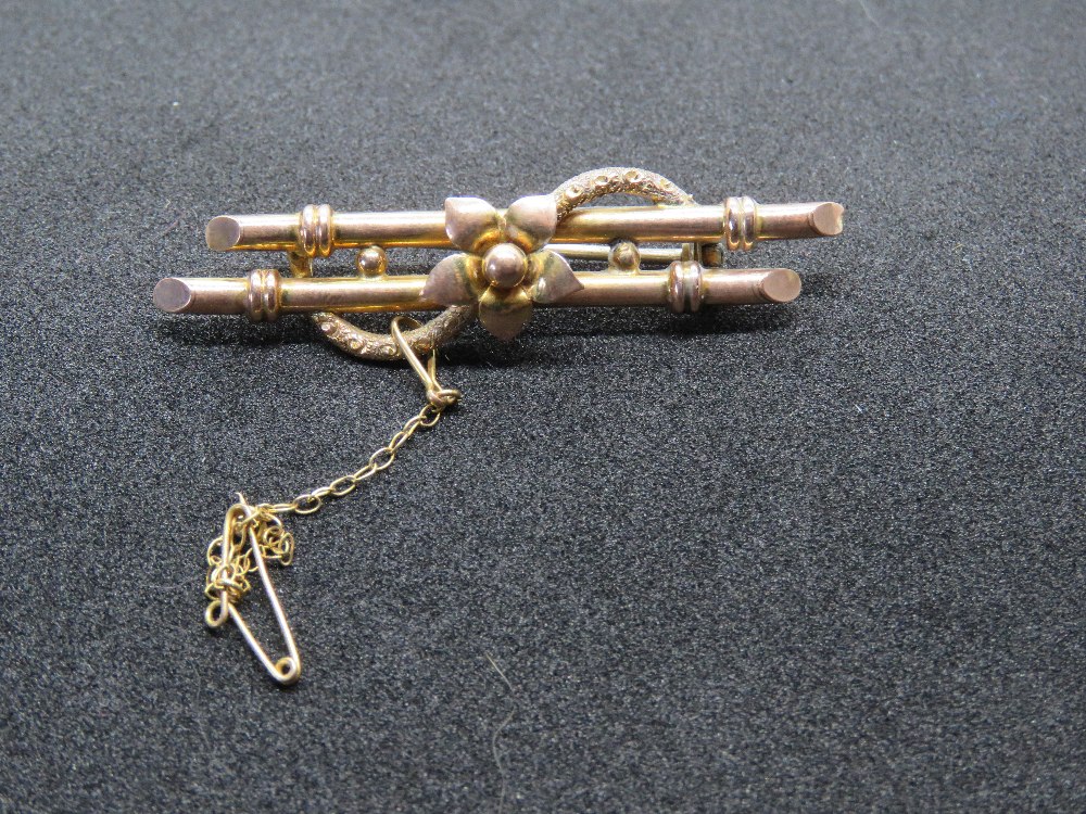 A vintage rose metal brooch having safety chain upon, no apparent hallmarks, 2.9g.