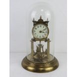 A brass mantel clock in glass dome having enamel dial, with key, all standing 31.5cm high.