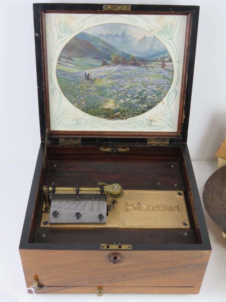 A walnut box Polyphone the lid lifting to reveal printed Swiss mountain scene to lid.