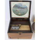 A walnut box Polyphone the lid lifting to reveal printed Swiss mountain scene to lid.