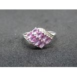 A 9ct white gold and pink sapphire ring, eight oval cut faceted stones in claw settings,