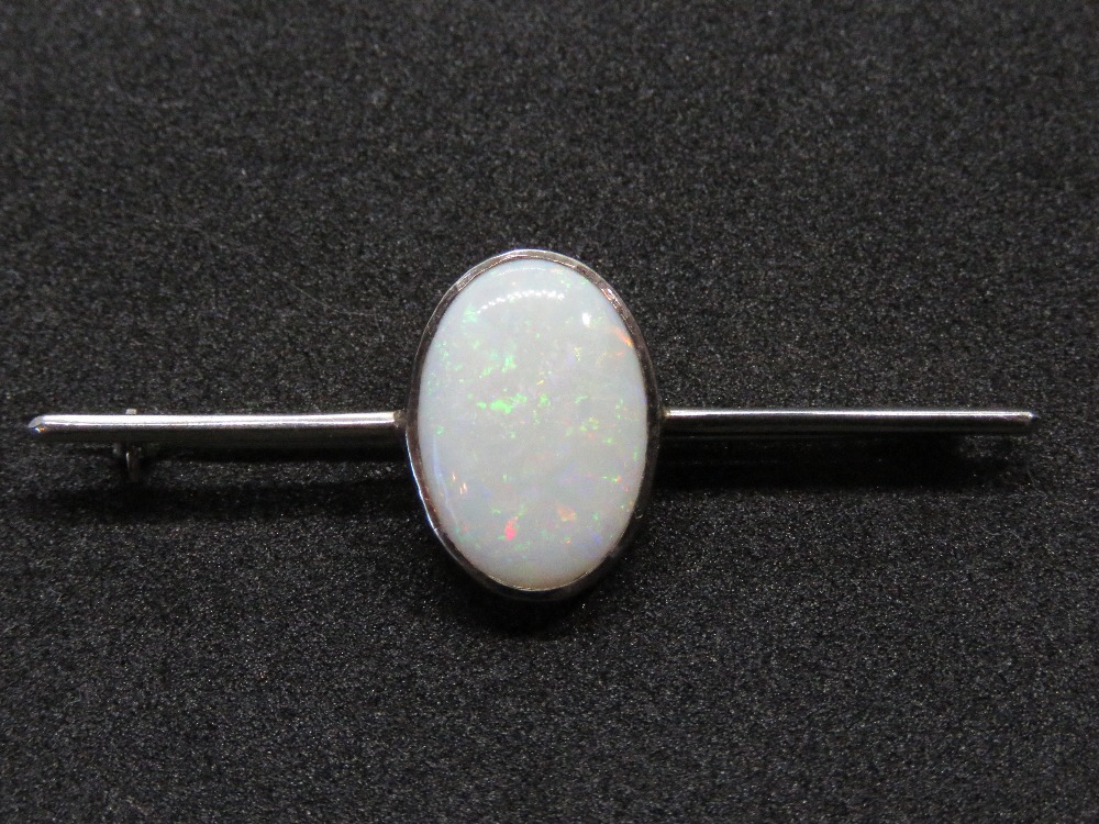 A 9ct white gold opal brooch, the large central oval cabachon approx 16 x 11mm,