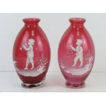 A pair of cranberry glass Mary Gregory type bud vases, each standing 14.5cm high.