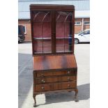 A bureau bookcase, the top having twin glazed doors opening to reveal shelves within,
