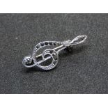 An Art Deco style silver and marcasite music themed brooch in the form of a treble clef.