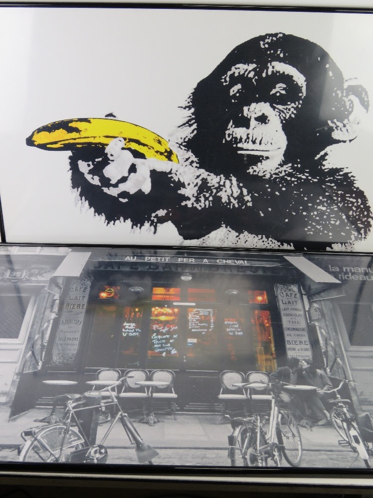 Two contemporary poster prints in frames being a chimp with banana and French cafe,