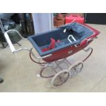 A Silver Cross dolls pram in red.