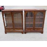 A matched pair of contemporary walnut quarter veneered twin door glazed bookcases having twin