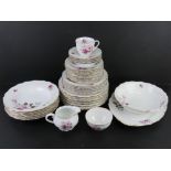 A white ground dinner service decorated with lilac and purple flowers, includes dinner plates,