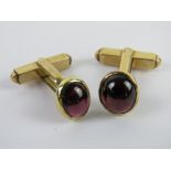A well made pair of hinged cufflinks having garnet coloured cabachons upon.