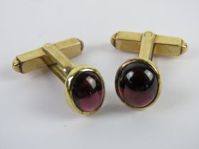 A well made pair of hinged cufflinks having garnet coloured cabachons upon.