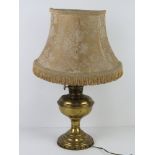 A brass oil lamp having been converted for use as an electric table lamp,