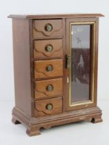 A contemporary wooden musical jewellery box having five drawers and glazed door.
