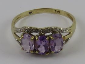 A 9ct gold three stone amethyst ring, stamped 375, size M, 1.5g.