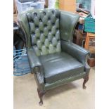 A green upholstered wing back arm chair approx 82cm wide, 1m high at back.