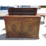 A late Victorian carved oak court cupboard having twin drawers with doors under,