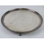 A large English made heavily silver plated circular serving tray raised over three ball and claw