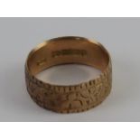 A 9ct gold wide band having engraved foliate decoration upon, hallmarked 375, size P, 4g.