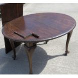 A c1930's oval wind out extending dining table raised over plain Queen Anne style legs,