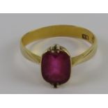 A 22ct gold ring having central faceted pink red oval stone in part rub over, part claw setting,