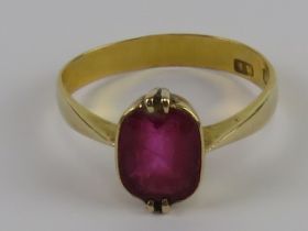 A 22ct gold ring having central faceted pink red oval stone in part rub over, part claw setting,