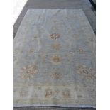 A large woollen rug in pale blue and cream ground measuring approx 203 x 291cm.