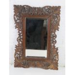 A Black Forest type carved wooden frame, good bevelled edge mirror within. Overall 37 x 52cm.