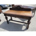 A late Victorian carved oak buffet or side table having twin frieze drawers with Green Man