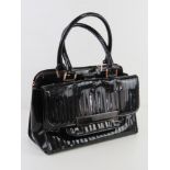 A black patent handbag by Ted Baker approx 34cm wide, some wear noted.