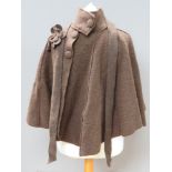 A brown 85% wool cape having flower applique upon.
