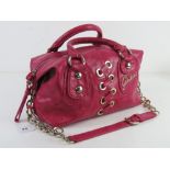 A hot pink handbag with shoulder strap by Guess, approx 30cm wide.