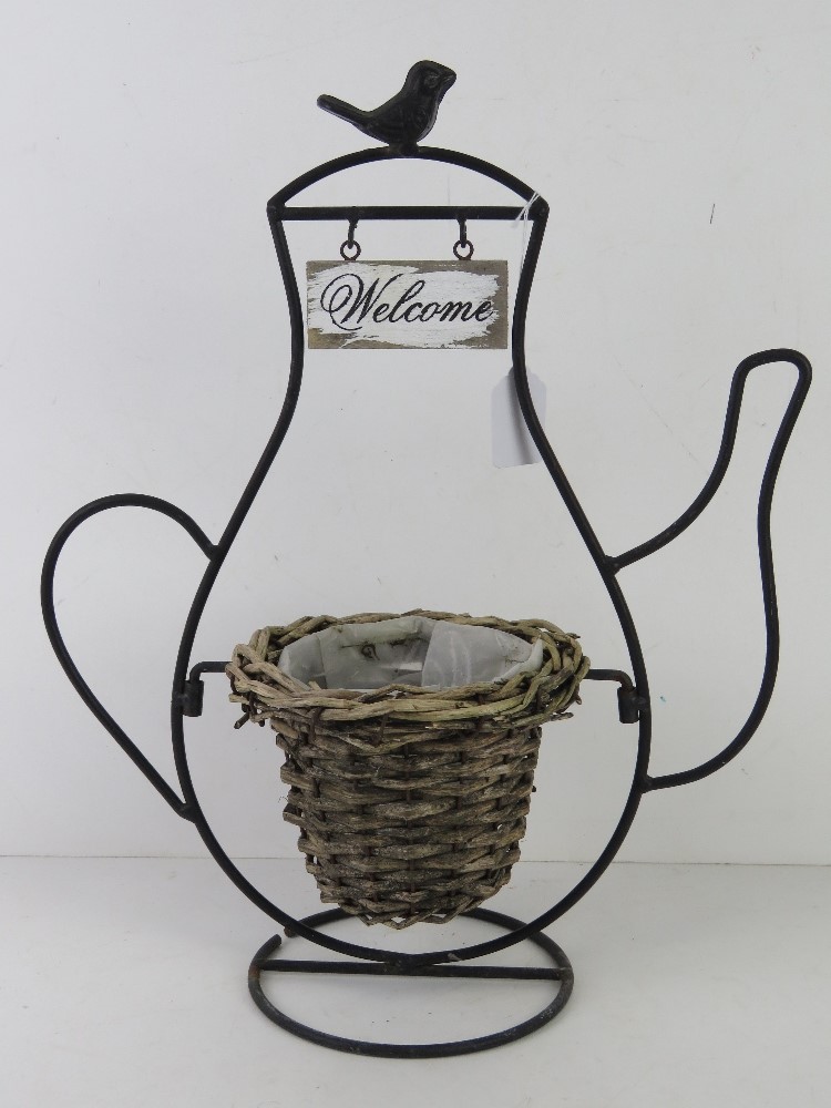 A teashop sign having wicker planter within black metal 'teapot' frame with Welcome sign over,