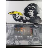 Two contemporary poster prints in frames being a chimp with banana and French cafe,