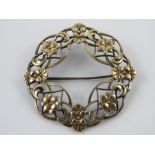 A Symmetalic Sterling silver and 14ct gold brooch of wreath form decorated with flowers, 4.5cm dia.