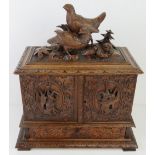 An impressive 19thC black forest carved tabletop cabinet having pair of partridges with chicks upon,