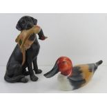 A hand made and painted wooden duck 41cm in length together with a figurine of a black Labrador with