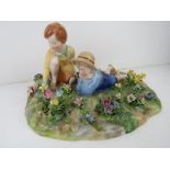 A Crown Staffordshire figurine of two children in a garden, modelled by T. Bayley.
