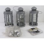 A set of three contemporary storm lanterns with a quantity of tea lights.