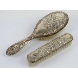 A HM silver backed hairbrush with matching HM silver backed clothes brush having repoussé CHerubic