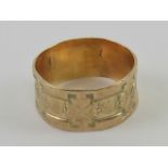 A yellow metal wide band having 3/4 floral engraving, no apparent hallmark, size Q, 3.1g.