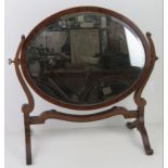 An Edwardian oval bevelled edge toilet mirror on shaped mahogany stand, 54 x 52cm.