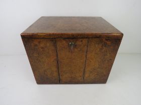 A walnut veneered campaign style humidor having twin doors with inset brass handles behind