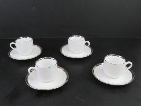 A set of four contemporary silver rimmed coffee cans with saucers.