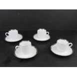 A set of four contemporary silver rimmed coffee cans with saucers.