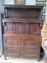 An 18th century oak court style cupboard having central field moulded panel to middle section and