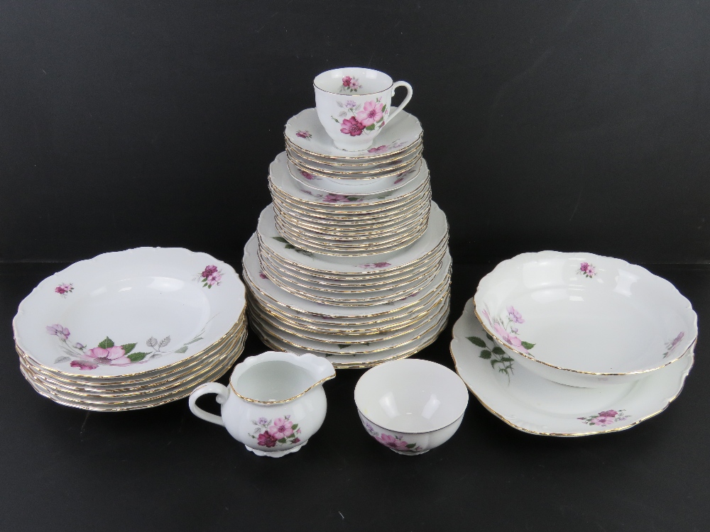 A white ground dinner service decorated with lilac and purple flowers, includes dinner plates,