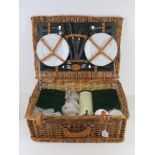 A wicker picnic basket for four by Marks & Spencer containing cutlery, plates, flask and tupperware,